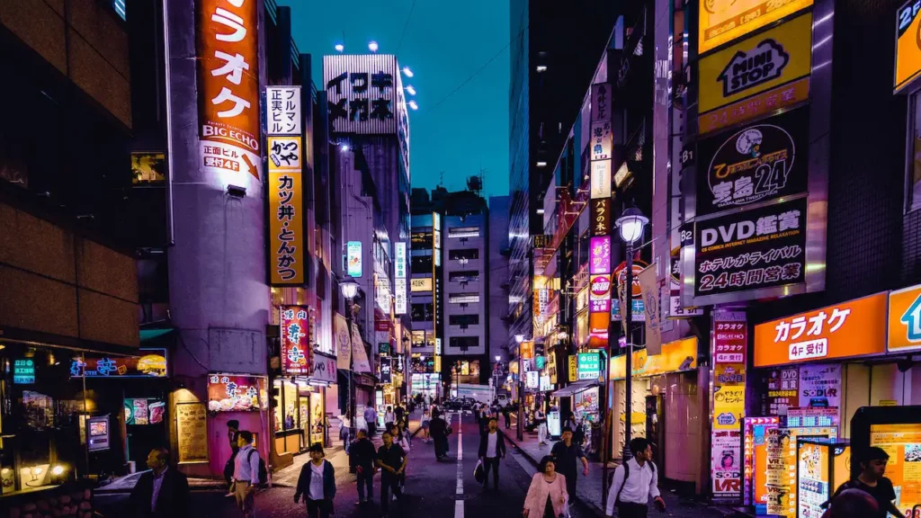 Des Gens Qui Marchent en pleine nuit Dans Les Rues de Tokyo Entourées De Bâtiments